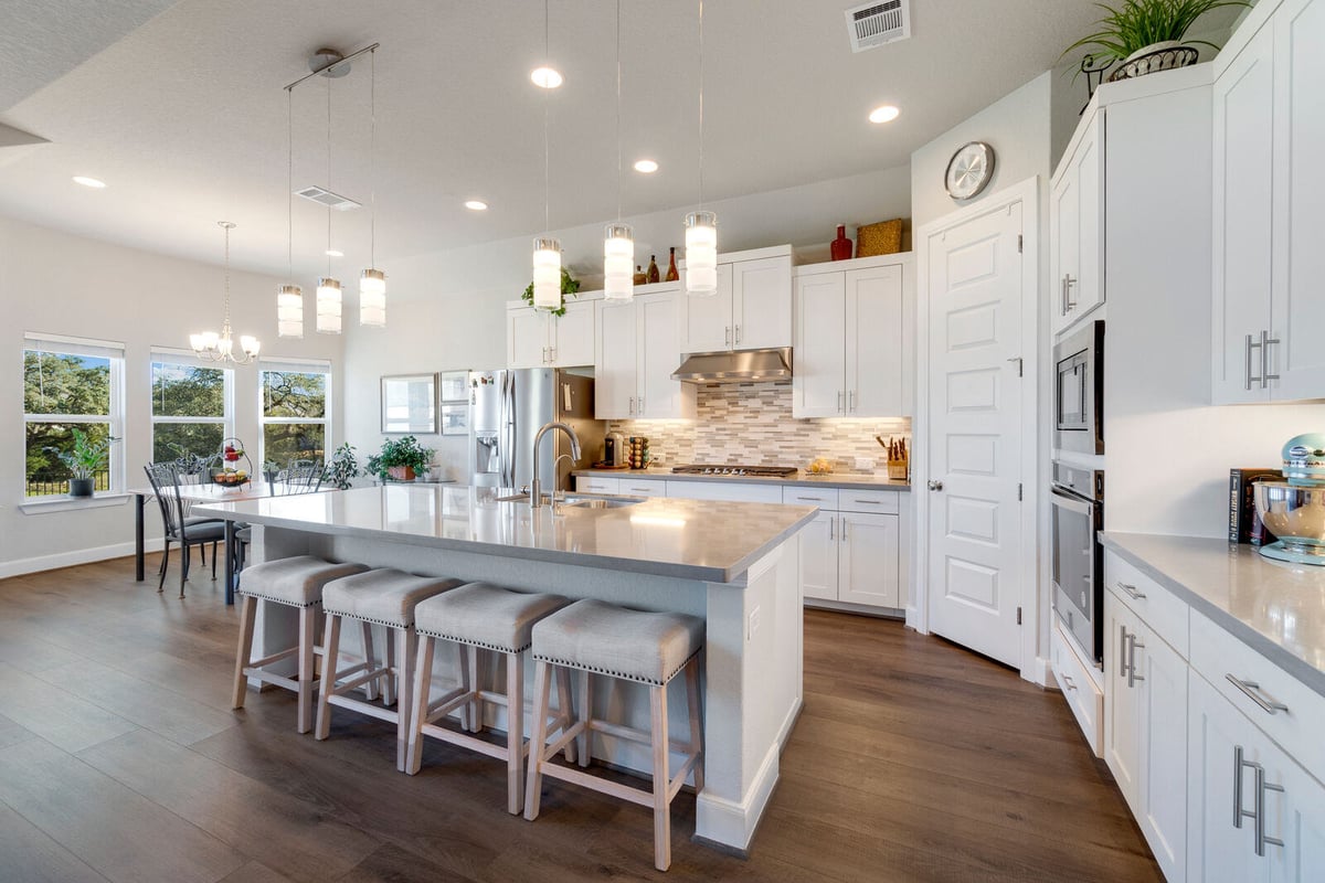 Contemporary kitchen remodel with a large quartz island and modern lighting by Triple Crown Contractors in Apex, NC