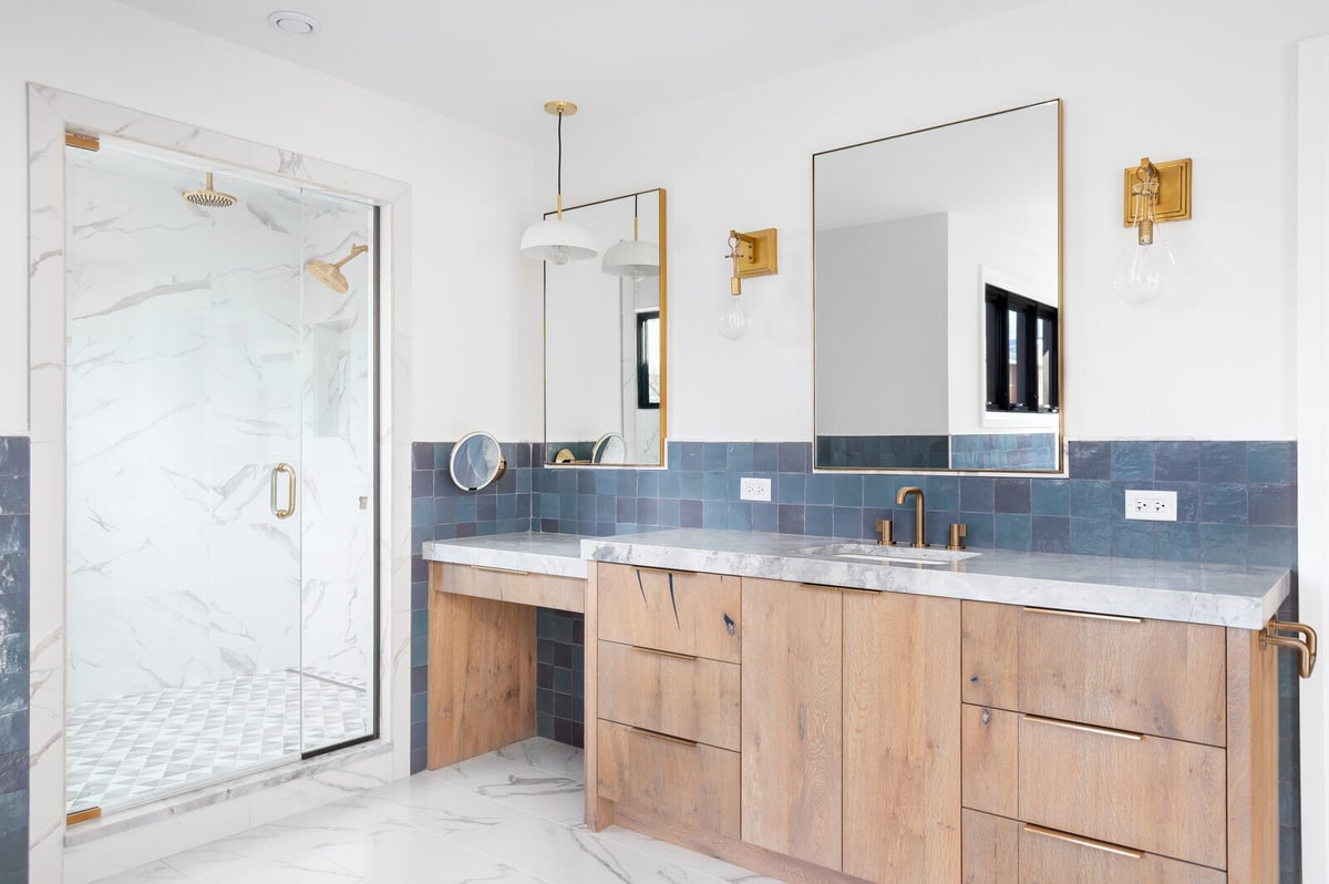 Modern luxury bathroom with marble flooring, custom wood vanities, and stylish blue tile accents, remodeled by Triple Crown Contractors in Apex, NC.jpg