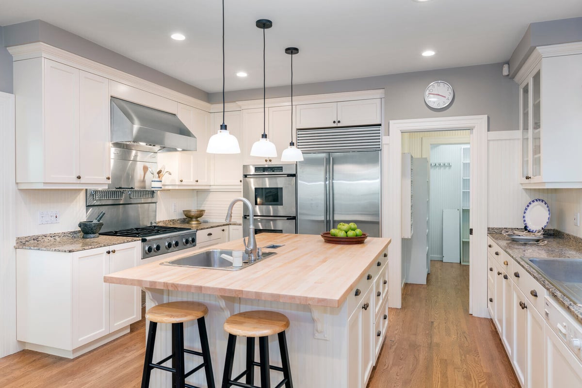 Open-concept kitchen with white cabinetry, stainless steel appliances, and pendant lighting in a renovated Durham, NC home