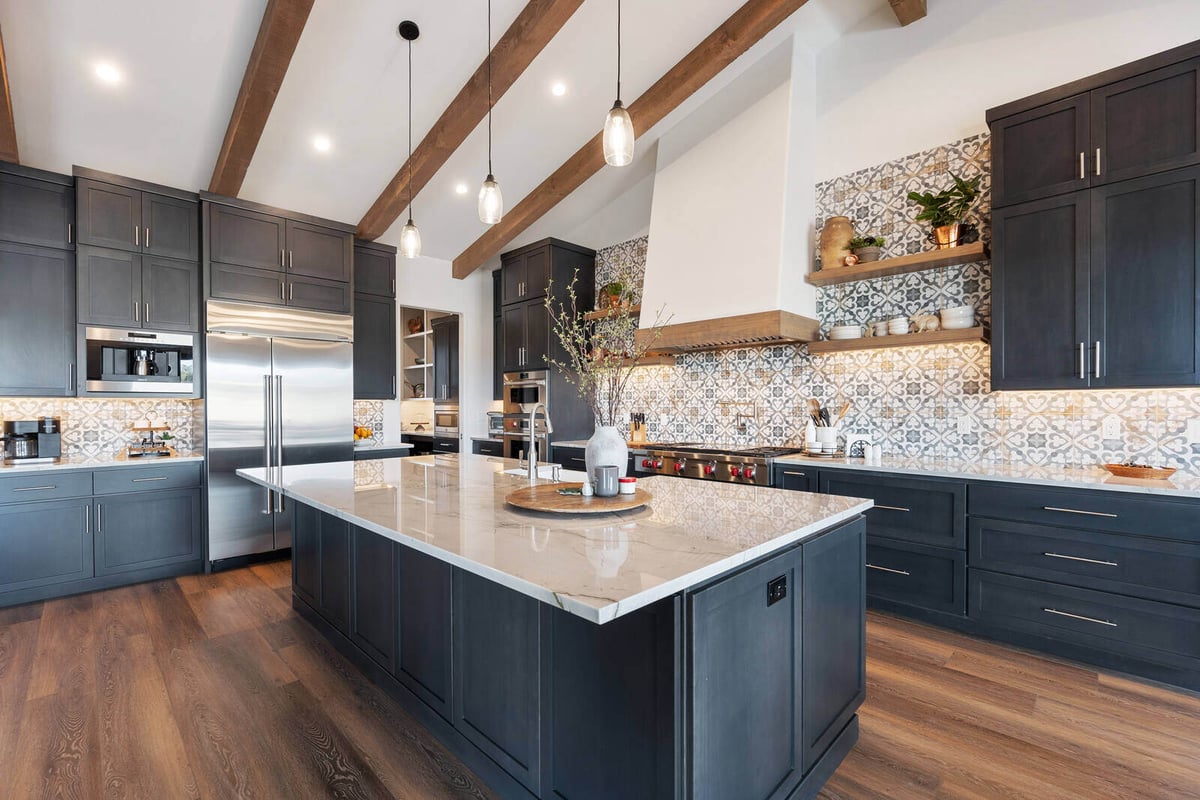 Rustic modern kitchen with dark cabinetry, exposed wood beams, and a large marble island, remodeled by Triple Crown Contractors in Apex, NC